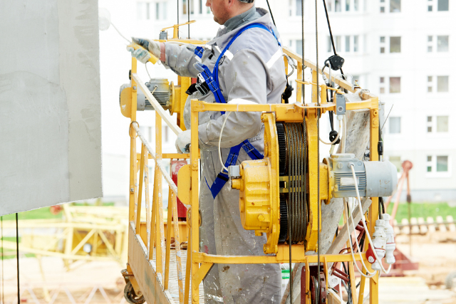 Commercial painter on fork lift painting the side of a building